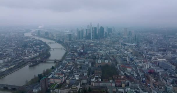 漠然とした日に大都市の空中パノラマ映像。広い川が市内を流れる。近代的なダウンタウンの高層ビルのグループ。フランクフルトはドイツのメインです — ストック動画