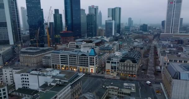 Tilt abajo tiro de edificios de varios pisos en el centro de la ciudad en el crepúsculo. Calles y zonas peatonales con tiendas. Rascacielos modernos en el fondo. Frankfurt am Main, Alemania — Vídeos de Stock