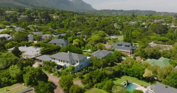 緑豊かな木々や低木に囲まれた家。後方の住宅街の上を家族の家で飛ぶ。背景に山を明らかにする。南アフリカ共和国ケープタウン — ストック動画