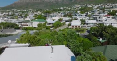 İlerlemeler, yerleşim bölgelerindeki yoğun gelişimin üzerinde uçar. Güneşli bir günde, tropikal seyahat noktalarındaki binalar ve pansiyonlar. Cape Town, Güney Afrika