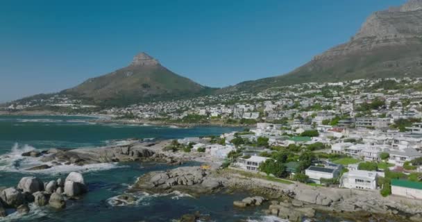 Terbang di atas pantai laut. Bangunan liburan di tujuan wisata. Pointed Lions Head mountain against clear blue sky in background. Cape Town, Afrika Selatan — Stok Video