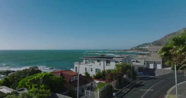 Letět nad domy na pobřeží oceánu v tropické oblasti. Slunečný a větrný den. Vlny se valí na břeh. Kapské Město, Jihoafrická republika — Stock video