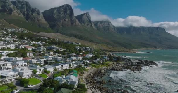 Fantastisk bild av havskusten. Rullande vågor, villor på solig sluttning under spektakulära klippiga bergsryggen. Kapstaden, Sydafrika — Stockvideo