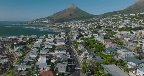 住宅や休暇のプロパティに囲まれた通りの上を飛ぶ。海辺の郊外と背景に急な斜面と山のピーク。南アフリカ共和国ケープタウン — ストック動画