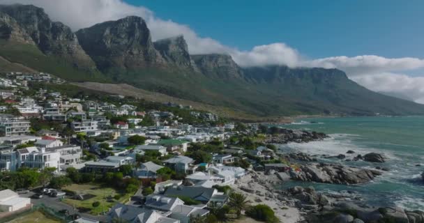 Adelante vuelan por encima de las villas y residencias de lujo en el barrio costero. Hermosa cresta de montaña con escarpes de roca escarpada. Ciudad del Cabo, Sudáfrica — Vídeo de stock