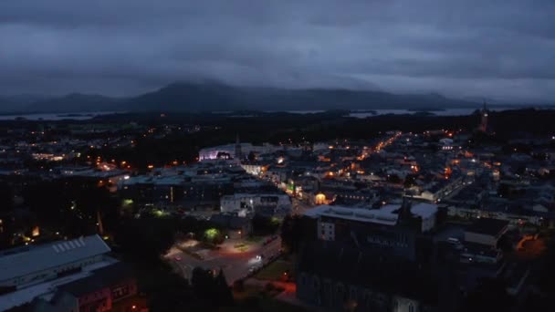 Vzdušné panoramatické záběry večerního města a hor kolem jezera v dálce. Osvětlené ulice. Killarney, Irsko — Stock video