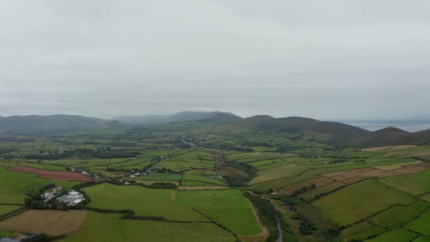 Εναέρια λήψη πράσινων λιβαδιών και λιβαδιών στην ύπαιθρο τη συννεφιασμένη ημέρα. Πανόραμα τοπίο με λόφους στο παρασκήνιο. Ιρλανδία — Αρχείο Βίντεο