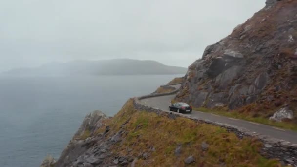 Autó vezetés keskeny úton kanyargós mentén sziklás lejtőn magasan a tengerpart felett. Lélegzetelállító utazás panorámás útvonalon. Írország — Stock videók