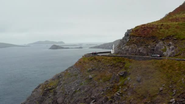 Slide és pan felvételek autók elhaladó Cross Slea Head. Fehér kőszobor belső görbén, tengerszint feletti magasságban. Írország — Stock videók