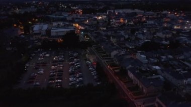 Banliyödeki cadde boyunca yüksek açılı binalar. Akşam kasabası ve tepeler görünüyor. Killarney, İrlanda