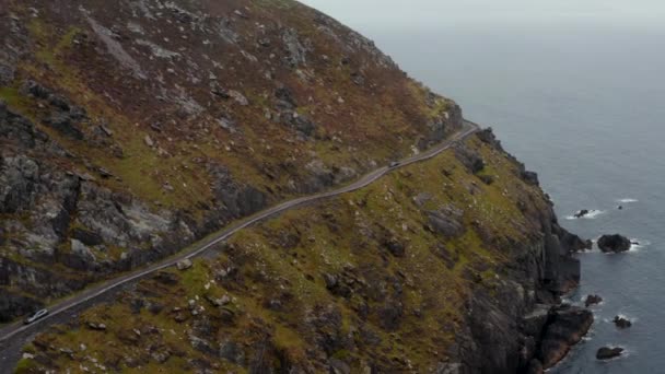 Oddech robi zdjęcie wolno poruszającego się samochodu na wąskiej trasie panoramicznej na stromym zboczu nad brzegiem morza. Niebezpieczna droga wokół Slea Head. Irlandia — Wideo stockowe