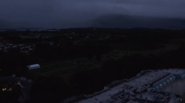Geriye dönükse, tarihi şehir merkezinin akşam olduğunu gösteriyor. Lüks bir otel binası ve eski bir kiliseyle düşük ışıklı şehir manzarası. Killarney, İrlanda
