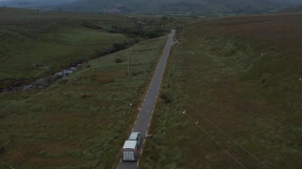말 트레일러와 함께 시골길을 달리는 차량을 추적하고 있다. 양 떼가 길을 따라 풀을 뜯고 있다. 아일랜드 — 비디오