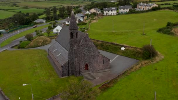 Vraag beelden op van oude stenen kerk op de weg in het dorp op het platteland. Een bewolkte hemel. Ierland — Stockvideo