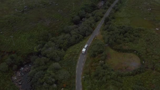 Forwards tracking of car with horse trailer driving on country road along stream. High angle view of valley with trees and shrubs. Ireland — Stock Video