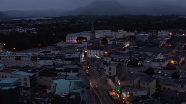 夕暮れ時に教会や高級ホテルと町の中心部の空中映像。バックライトの通りに沿って建物の明らかにする。アイルランドのキラーニー — ストック動画