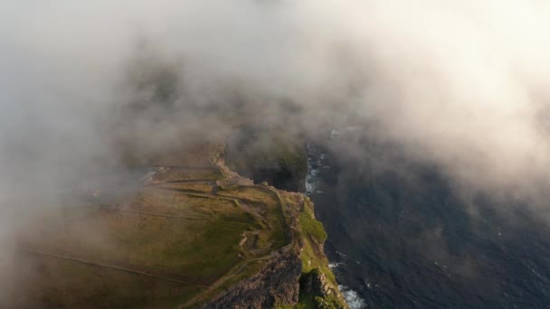 Imagens aéreas de falésias costeiras envoltas em nuvens baixas. Cenário pitoresco da hora dourada. Cliffs of Moher, Irlanda — Vídeo de Stock
