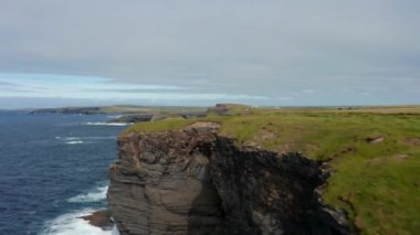 Yüksek uçurumlar boyunca uç. Dalgalanan deniz yüzeyinin üzerindeki dikey kaya duvarları. Güzel manzara manzarası. Kilkee Cliff Walk, İrlanda