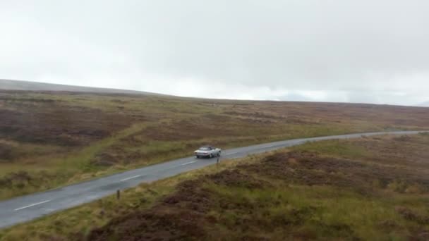 Śledzenie pojedynczego zabytkowego samochodu kabrioletowego z tekstylnym dachem jazdy po drodze na wsi w pochmurny dzień. Irlandia — Wideo stockowe