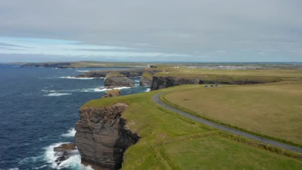 Fly above meadow above high cliffs steeply falling to sea surface. Aerial panoramic footage of natural landmark. Kilkee Cliff Walk, Ireland — Stock Video
