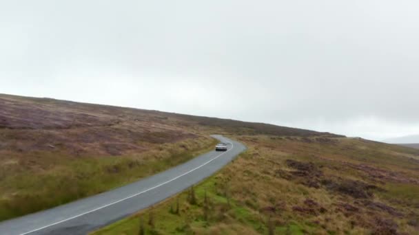 Seguimiento hacia adelante coche convertible en la carretera con curvas húmedas rodeado de prados y pastizales en el campo. Irlanda — Vídeo de stock