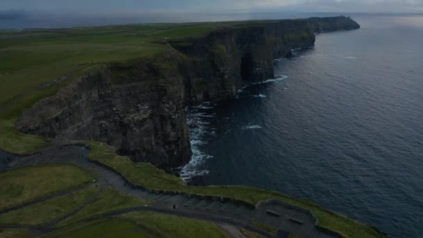 High angle view of panoramic tourist route on edge of rocks with amazing view on high rocky cliffs above sea surface. Natural scenery at sunset. Cliffs of Moher, Ireland — Stock Video