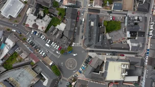 Luftaufnahmen zeigen von oben nach unten aufsteigende Autos, die durch den Kreisverkehr in der Innenstadt fahren. Stadtentwicklung aus der Höhe. Ennis, Irland — Stockvideo