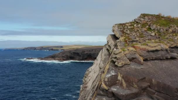 Framåt flyger runt klippblock. Avslöjande panoramautsikt över havskusten och det kuperade blå havet. Kilkee Cliff Walk, Irland — Stockvideo