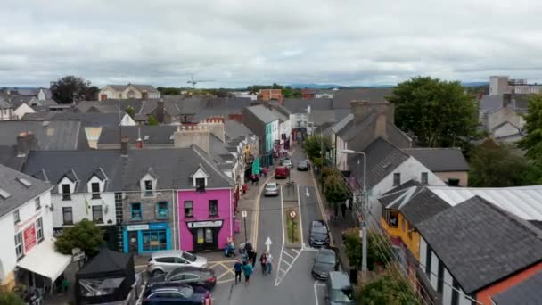 Forwards fly above narrowing street in town centre. Shops and services in houses along street. Ennis, Ireland — Stock Video