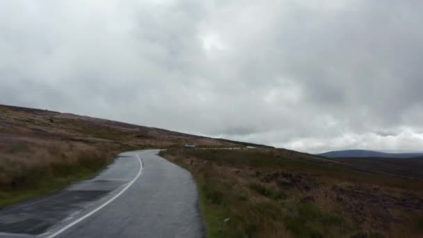 Avante voar ao longo da estrada e rastreamento de carro de prata no dia nublado. Rota curvilínea estreita através das terras altas. Irlanda — Vídeo de Stock