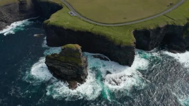 Flygfoto över kokande vatten vid kustklippor. Fantastisk bild av höga klippor och grönt gräs med väg på toppen. Kilkee Cliff Walk, Irland — Stockvideo