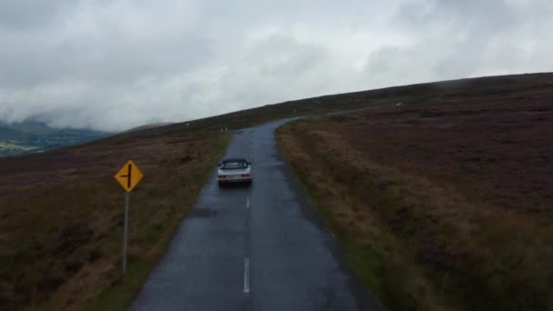 Twee auto 's passeren elkaar op smalle natte weg in de hooglanden. Bewolkte herfstdag op grote heidevelden. Ierland — Stockvideo