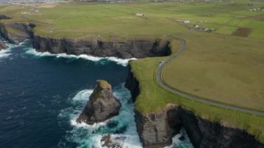 Güzel bir kıyı manzarası. Yüksek kaya kayalıklarının ve su sıçratan dalgaların havadan panoramik görüntüsü. Kilkee Cliff Walk, İrlanda