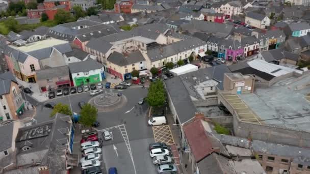 Κυκλική λήψη του κέντρου της πόλης. Πλατεία με κυκλικό κόμβο και σταθμευμένα αυτοκίνητα. Εμπορικοί δρόμοι τριγύρω. Ennis, Ιρλανδία — Αρχείο Βίντεο