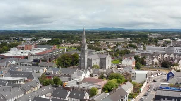 Slide and pan aerial footage of historic stone cathedral surrounded by town development. Ennis, Ireland — Stock Video