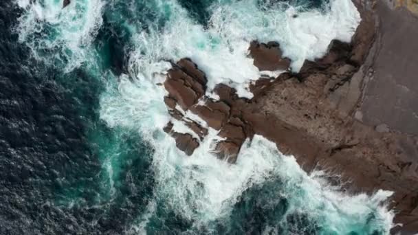 Volatili aerei occhio sopra vista dall'alto verso il basso della massa di acqua che si schianta sulla costa di pietra dura, schizzi e fare schiuma. Kilkee Cliff Walk, Irlanda — Video Stock