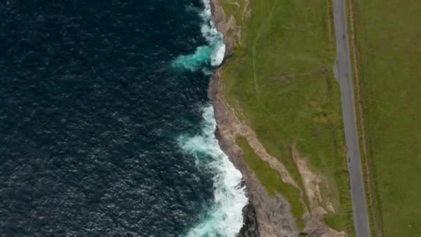 Flygfåglar ögon ovanför toppen ner utsikt över vågor rullar till kusten och kraschar på klippor. Flyg över havskusten. Kilkee Cliff Walk, Irland — Stockvideo