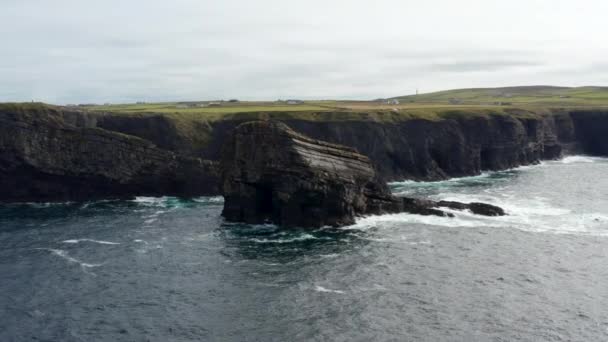 Slide och skott av stora stenblock stiger från vattnet vid havskusten. Hårda havsvågor som kraschar mot stenar. Kilkee Cliff Walk, Irland — Stockvideo