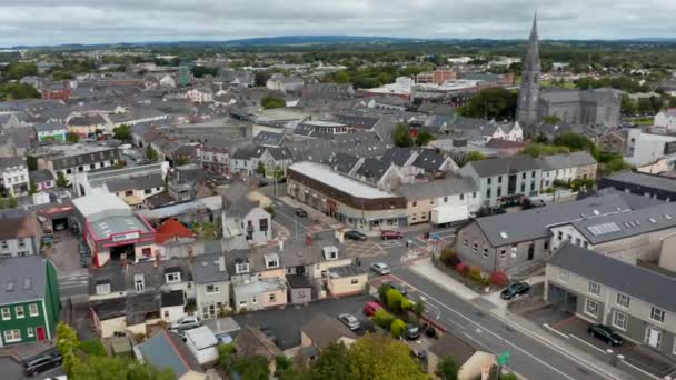 Filmagem panorâmica aérea de edifícios no centro da cidade. Incline-se para baixo com foco em carros que passam pelo cruzamento de rua. Ennis, Irlanda — Vídeo de Stock