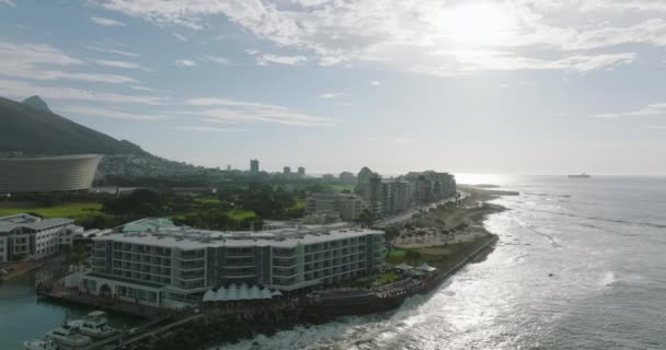 Hotele i budynki mieszkalne wzdłuż wybrzeża morskiego. Fale płyną na brzeg i myją plażę. Miejska dzielnica Mouille Point. Kapsztad, Republika Południowej Afryki — Wideo stockowe