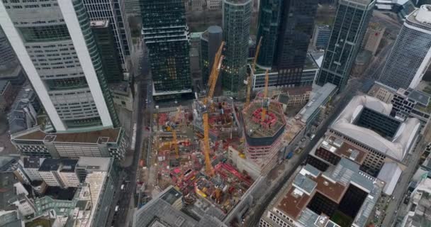High angle shot of construction site of new building. Orange tower cranes and machinery. Tilt up reveal of downtown skyscrapers. Frankfurt am Main, Germany — Stock Video
