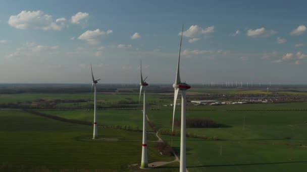 Vola intorno a turbine eoliche che producono energia pulita da fonti naturali. Paesaggio pianeggiante con campi verdi. Concetto di energia verde, ecologia e riduzione dell'impronta ecologica — Video Stock