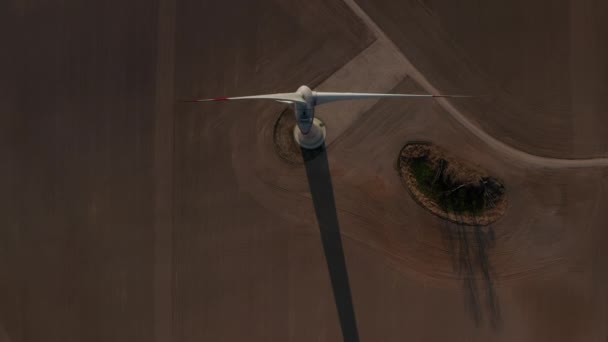 Záběr větrné turbíny shora dolů uprostřed pole. Rotační rotor proti hnědé půdě na zemědělském poli. Zelená energie, ekologie a koncepce snižování uhlíkové stopy — Stock video