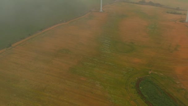 Vista de alto ângulo do campo de grãos no dia nebuloso. Incline-se revelar de turbina eólica única. Conceito de energia verde, ecologia e redução da pegada de carbono — Vídeo de Stock