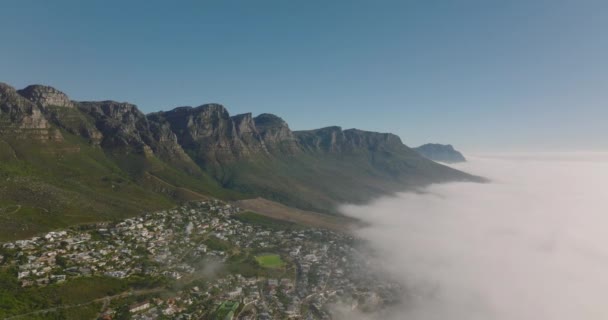 Удивительные панорамные снимки скалистого горного хребта, поднимающегося над ландшафтом, затопленным прибрежным туманом. Кейптаун, ЮАР — стоковое видео