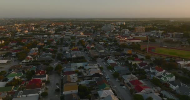 Nagranie zstępujących budynków w mieście o zmierzchu. Przód przelatuje nad ulicami i domami. Port Elisabeth, Republika Południowej Afryki — Wideo stockowe