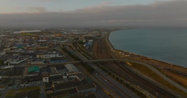 Jalan raya dan kereta api di sepanjang pantai laut. Pemandangan udara infrastruktur transportasi di kota saat senja. Port Elisabeth, Afrika Selatan — Stok Video