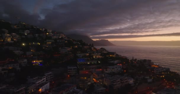 夕暮れ時に住宅街の高架映像を撮る息。海の海岸に落ちる斜面の豪華な住宅。南アフリカ共和国ケープタウン — ストック動画