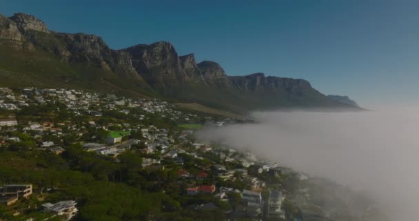 Flygbilder av höga klippiga bergskammar som reser över resmålet och dimma översvämmade havskusten. Kapstaden, Sydafrika — Stockvideo