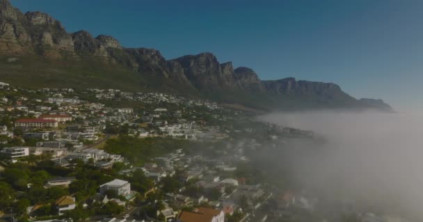 Statisk bild av turistiska resort vid havet med hög stenig sluttning i bakgrunden. Morgondimman stiger från vattenytan. Kapstaden, Sydafrika — Stockvideo